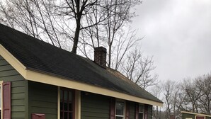 Uma casa pequena, térrea, com varanda frontal e um lance de escadas que dá acesso à entrada.
