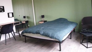Et soveværelse med seng, skrivebord, stol og et natbord.