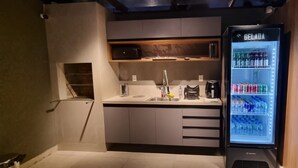 A compact kitchen with a built-in refrigerator displaying various beverages. - Pipa Day Flats (Tibau do Sul)