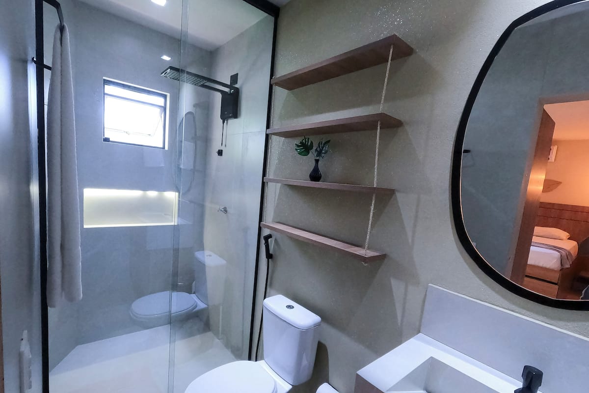 A modern bathroom with a glass-enclosed shower, a white toilet, a sink, and a mirror.