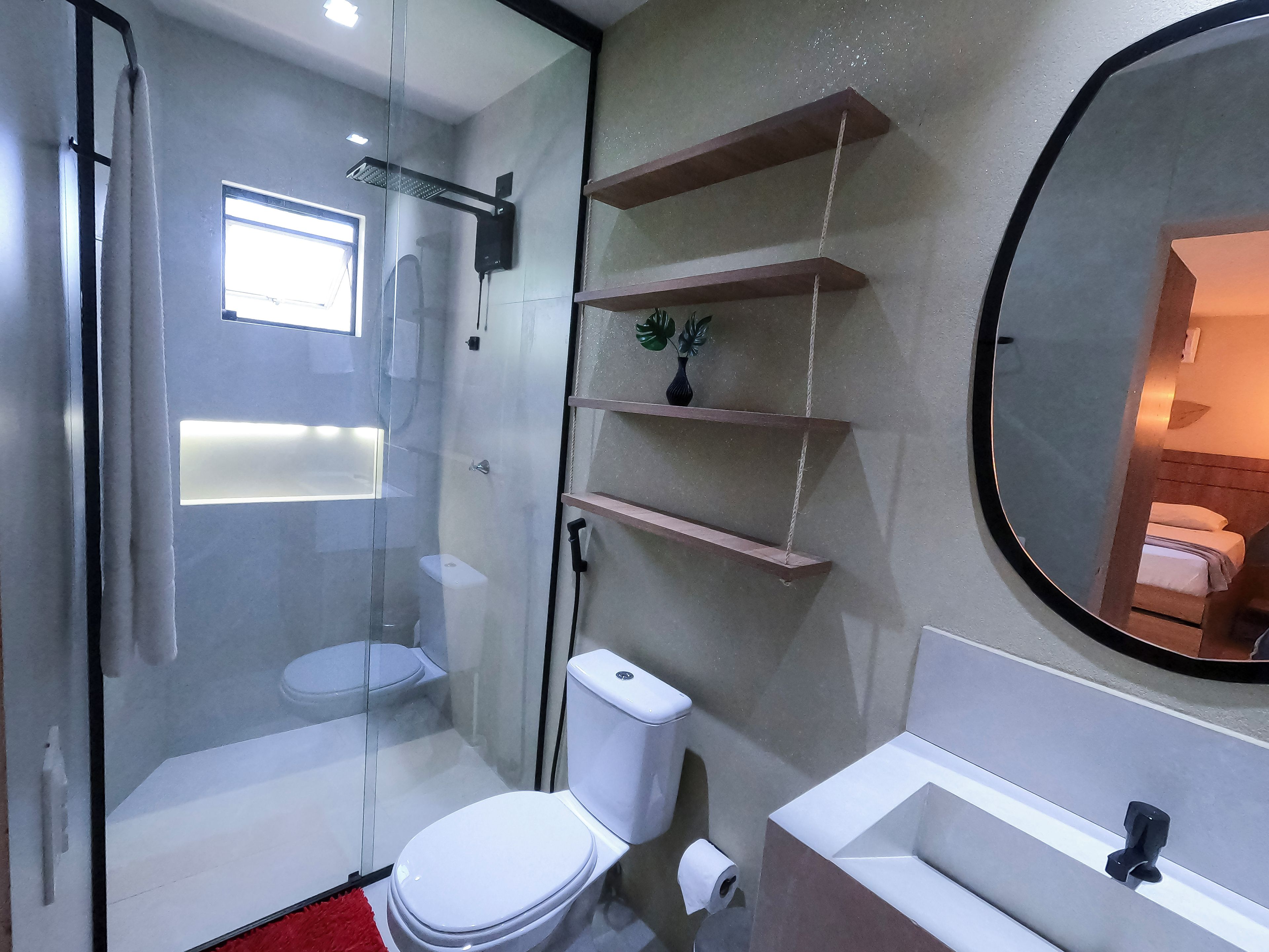 A modern bathroom with a glass-enclosed shower, a white toilet, a sink, and a mirror.
