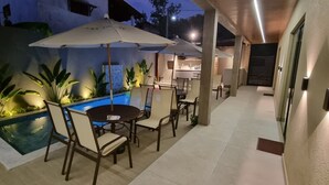 An outdoor patio area with a pool, chairs, and umbrellas. - Pipa Day Flats (Tibau do Sul)