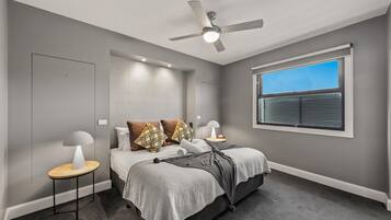 A bedroom with a bed, bedside tables, a ceiling fan, and a window.