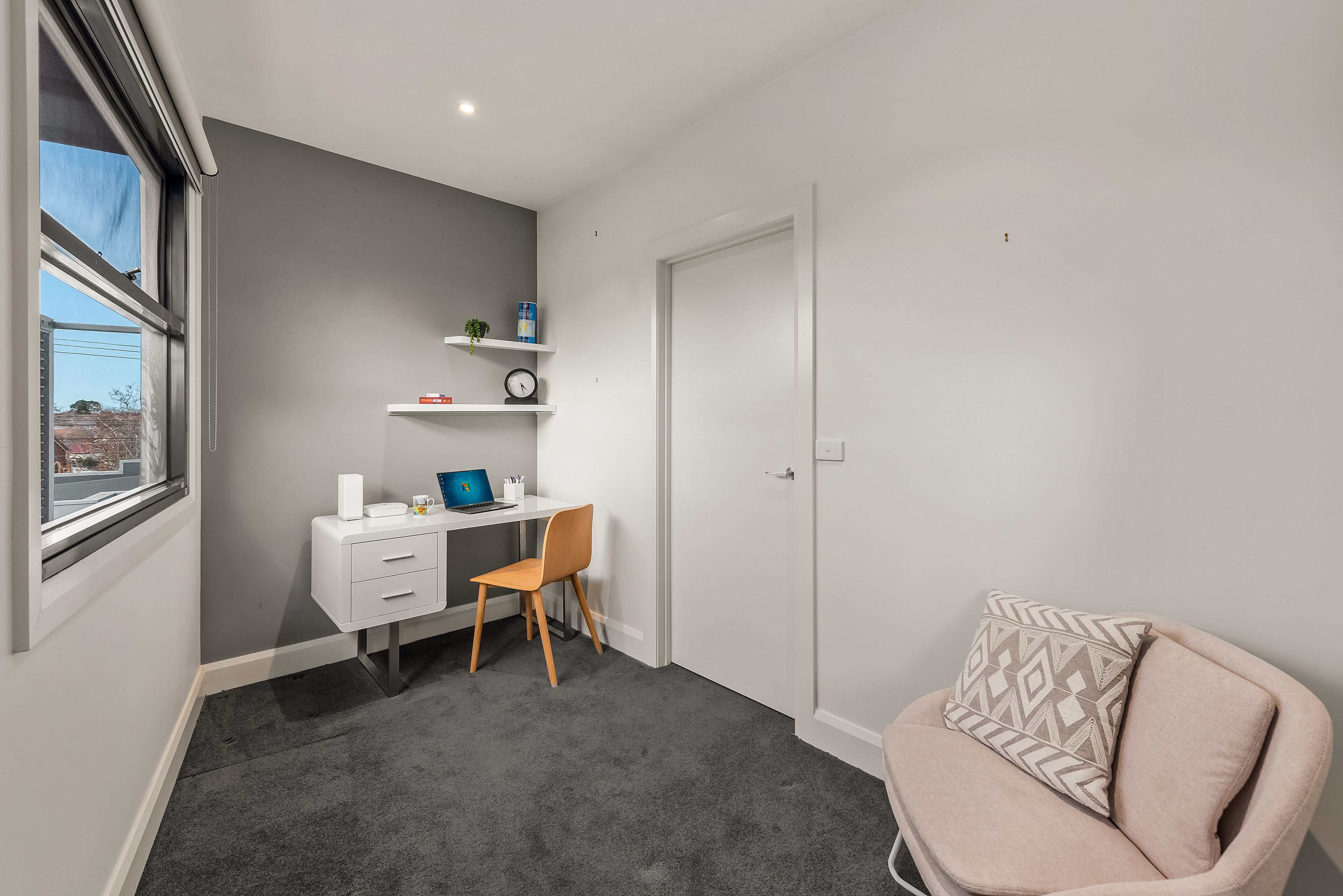 Une petite pièce moderne équipée d’un bureau, d’une chaise et d’un coin salon confortable.