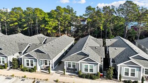 A row of modern, single-story houses with sloped roofs and large windows, surrounded by trees and a clear sky. - 1385 - Stay Awhile - Cozy Corolla Getaway Near Beach & Community Pool (Corolla)