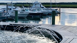 Un port de plaisance avec des bateaux amarrés à des quais en bois, une eau calme et un ciel nuageux.