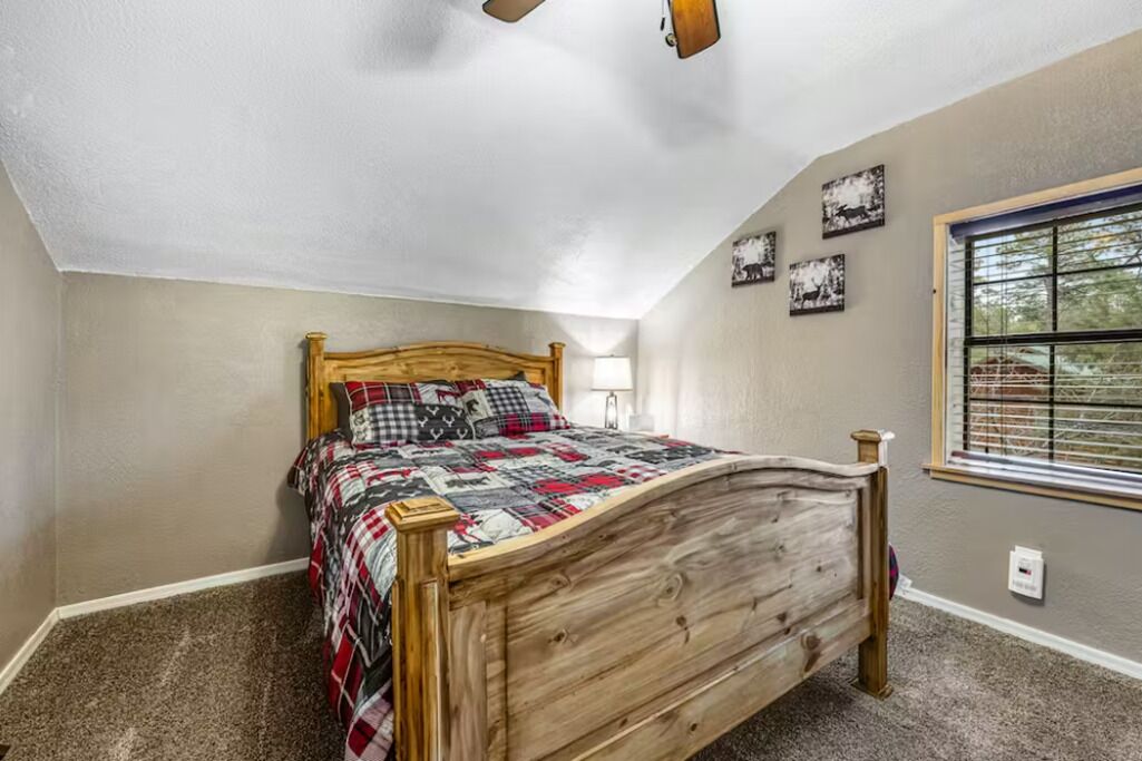 A bedroom with a wooden bed, a ceiling fan, and a window with blinds.