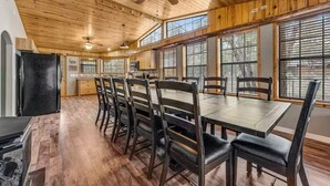A spacious kitchen with wooden cabinets, a large dining table, and a ceiling fan. - Incredible Rustic Lakeside Cabin in the Woods! Near Lakes, Skiing and Trails! (Lakeside)