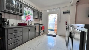 Una cucina con mobili grigi, un fornello e un frigorifero.