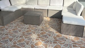 A covered outdoor seating area with a large sectional sofa and wicker furniture, set on a stone-tiled floor. - Relaxing 3 bedroom pool home (Miami)