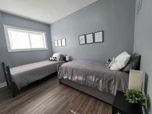 Una camera da letto con due letti singoli, una finestra e opere d'arte appese al muro.