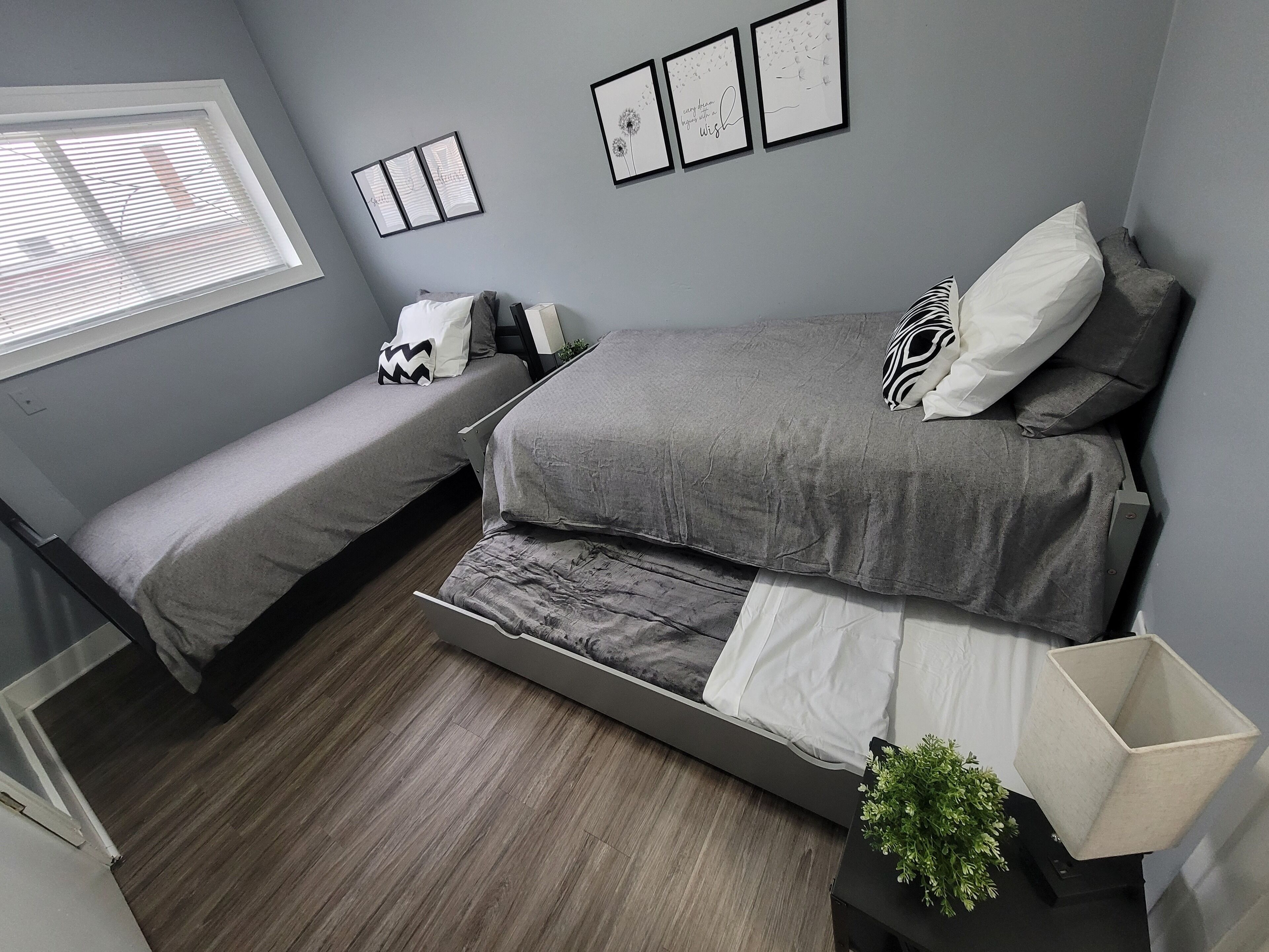 Een slaapkamer met een bed, een extra slaapgedeelte, een raam en wanddecoratie.