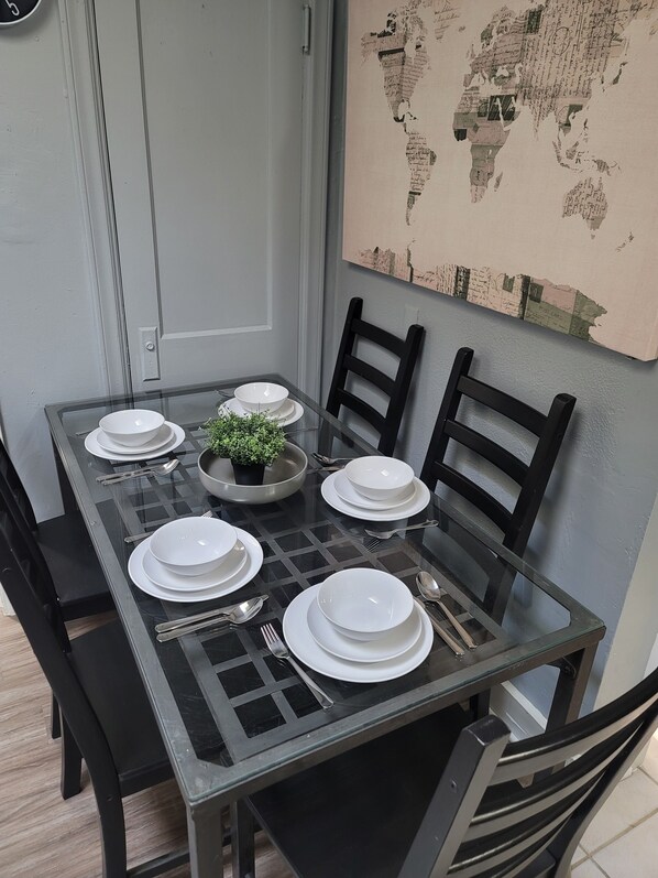 A dining table set with white plates, silverware, and a small potted plant.