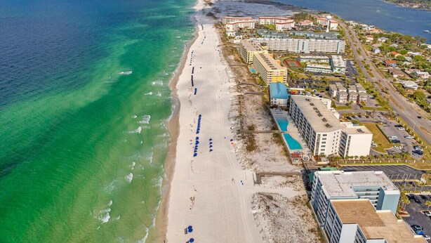 A coastal hotel with a beach view, multiple buildings, and a parking area. - Seacrest Beachfront 2BR | Angled Gulf View + Pools (Fort Walton Beach)