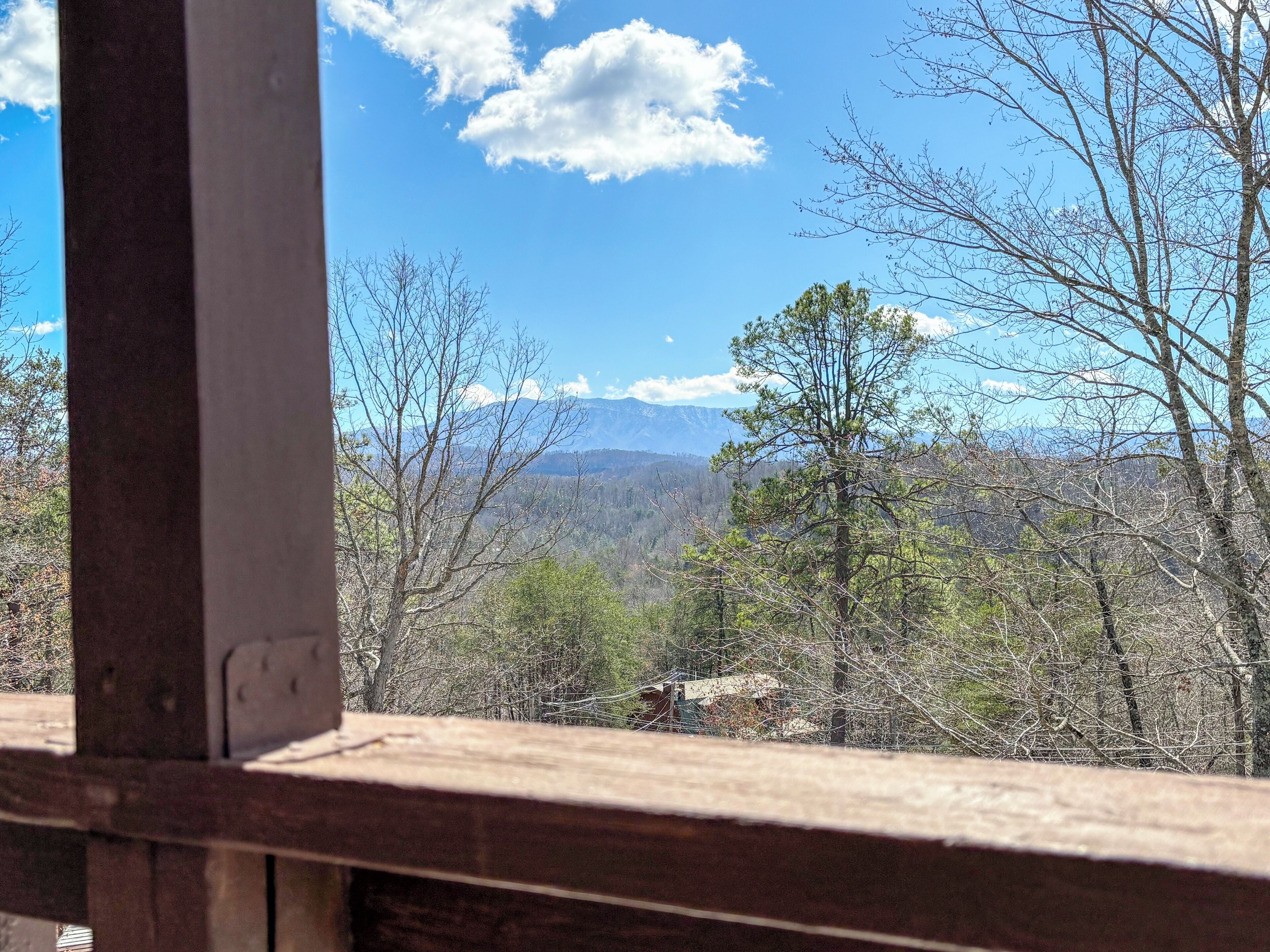 A view from a window overlooking a mountainous landscape with trees and a clear sky.