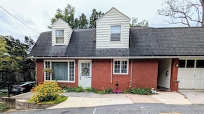 Ein eingeschossiges Haus mit roter Backsteinfassade, dunklem Schindeldach und Garage.