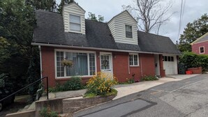 A two-story house with a gabled roof, a front porch, and a garage. - Charming 2BR Private Home in Downtown Bellefonte • Near Penn State & I-80 (Bellefonte)