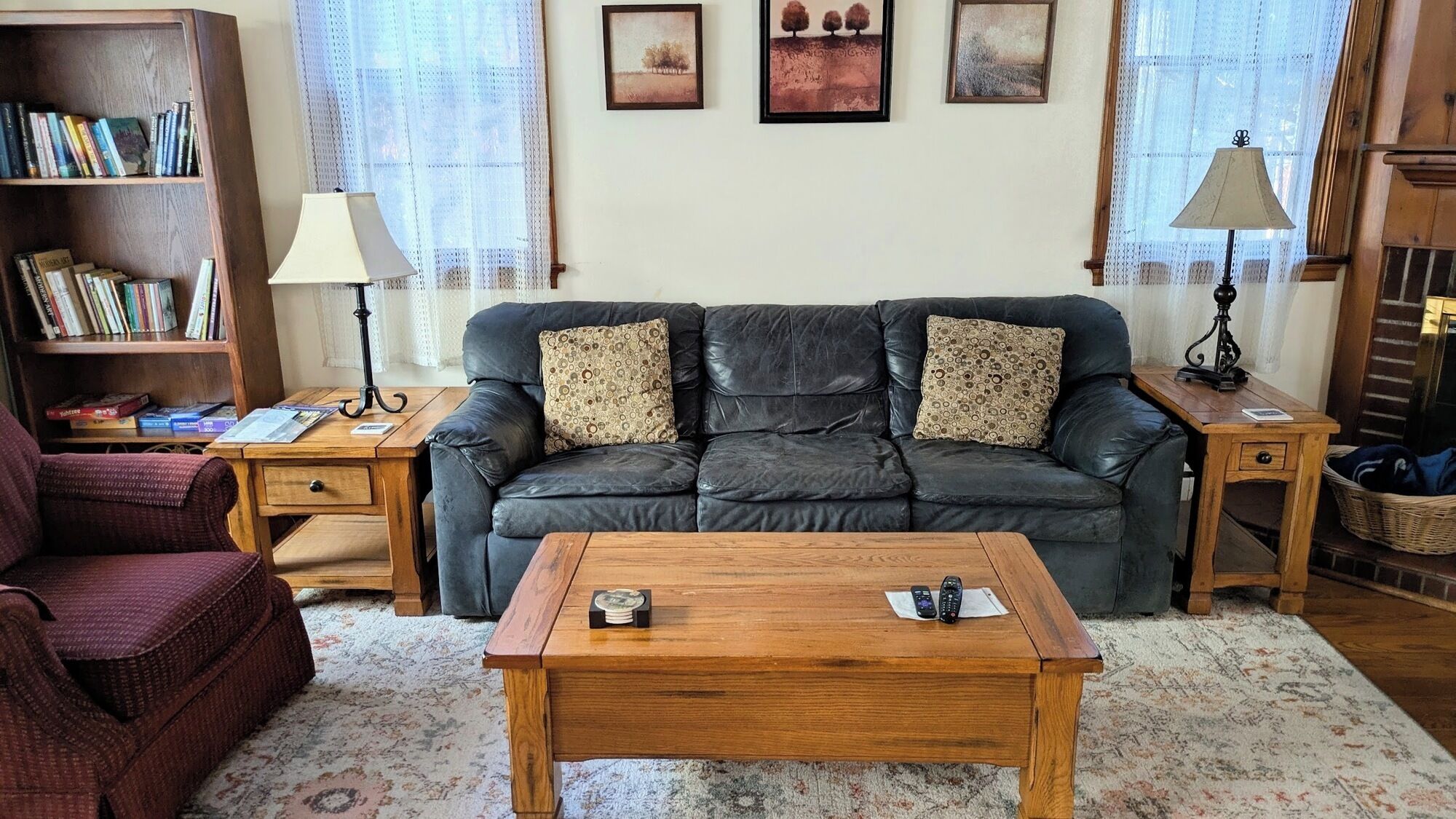 Ein gemütliches Wohnzimmer mit Ledersofa, Couchtisch aus Holz, Bücherregal und zwei Lampen.