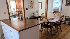 A kitchen with wooden cabinets, a dining table with chairs, and a fireplace. - Charming 2BR Private Home in Downtown Bellefonte • Near Penn State & I-80 (Bellefonte)