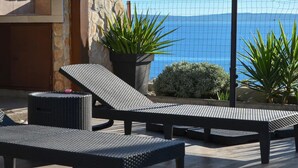 Un patio con dos sillones, una mesita y plantas en macetas.
