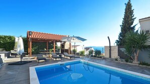 A swimming pool with lounge chairs and umbrellas, a pergola, and a view of the sea. - Wonderful quiet beach location 5 km from Trogir, swimming pool, sea view (Okrug Gornji)