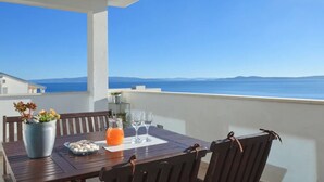 A wooden table with chairs on a balcony overlooking the sea, a potted plant, a glass pitcher of orange juice, and two wine glasses. - Wonderful quiet beach location 5 km from Trogir, swimming pool, sea view (Okrug Gornji)