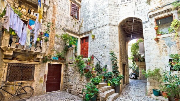 A narrow cobblestone street with stone buildings, a bicycle, and potted plants. - Wonderful quiet beach location 5 km from Trogir, swimming pool, sea view (Okrug Gornji)