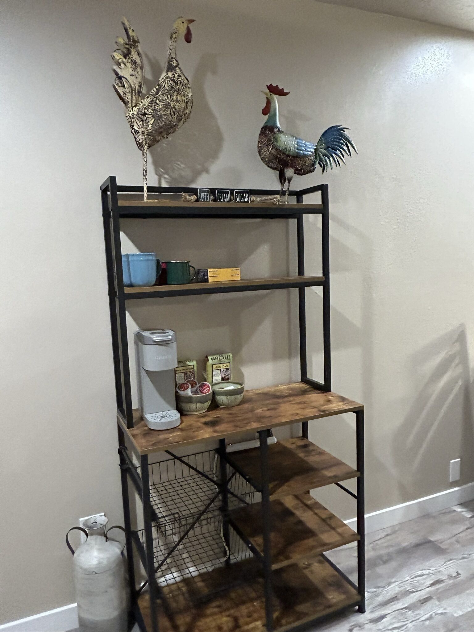 A black metal shelf unit with decorative rooster figures, a coffee maker, and various kitchen items.