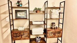 Een houten rek met verschillende vakken, waarvan sommige gevuld zijn met opgevouwen handdoeken en decoratieve objecten.