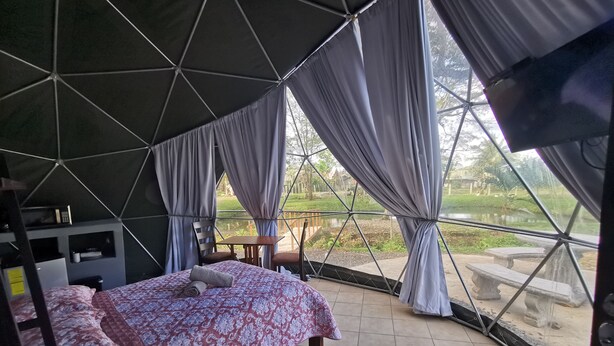A tented accommodation with a bed, a small table, and a chair. - Domo Geodésico 01 (Florencia)