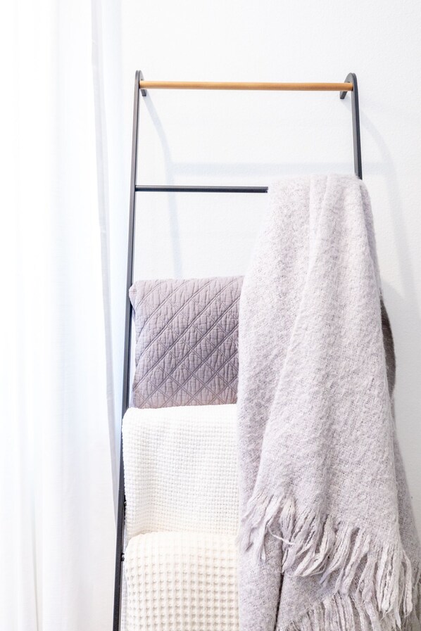 A metal rack with three blankets hanging on it.