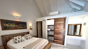 Een slaapkamer met een houten bed, een schilderij aan de muur, een kledingkast en een spiegel.