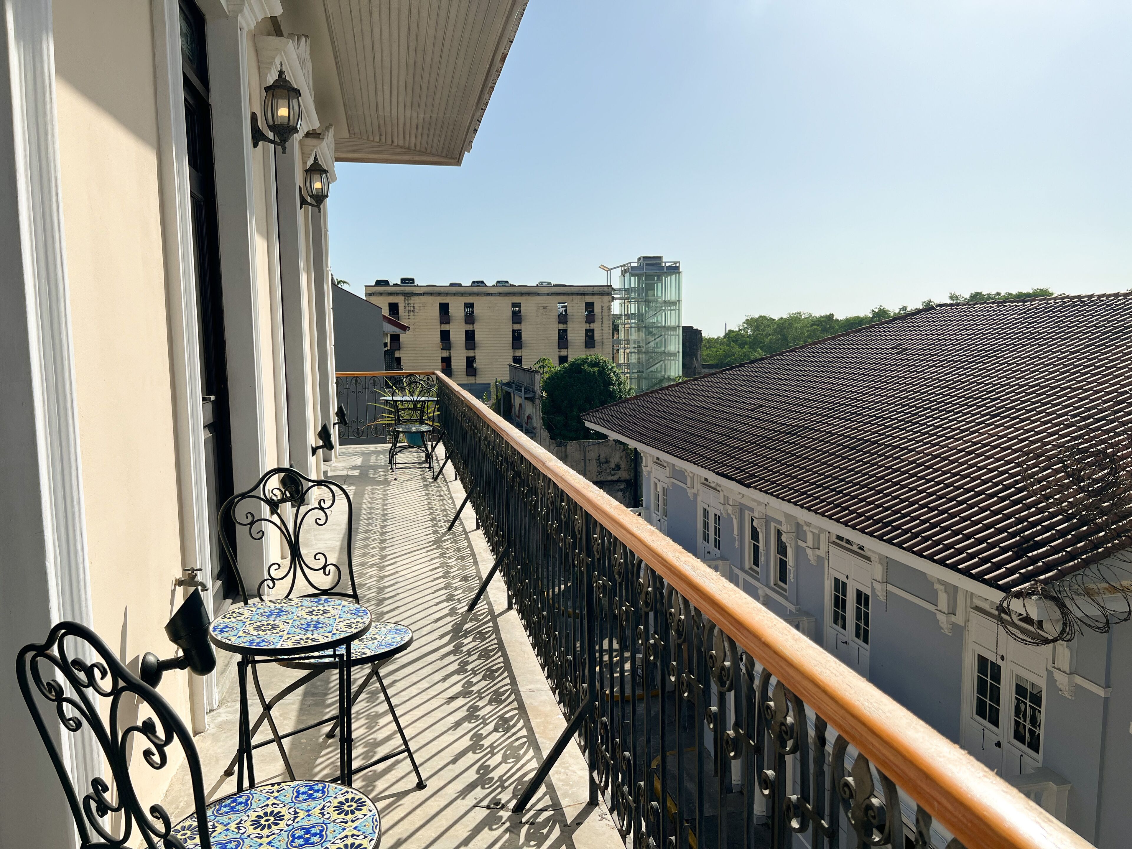 A balcony with a table and chairs, a railing, and a view of buildings in the background.