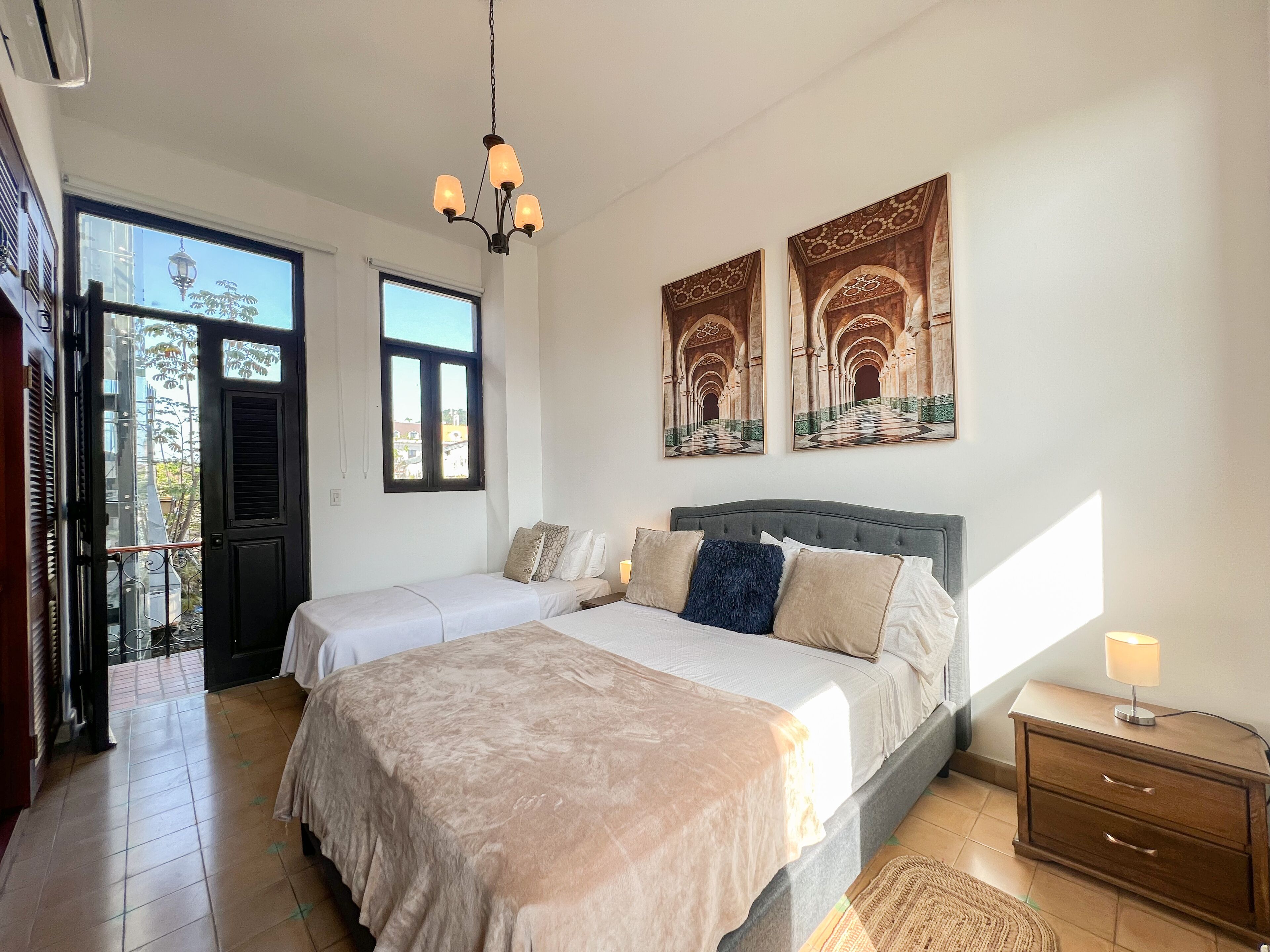 Une chambre avec deux lits, un lustre, des œuvres d’art et une vue par la fenêtre.