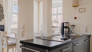 A modern kitchen with a black countertop, stainless steel appliances, and a window with a view of a building.