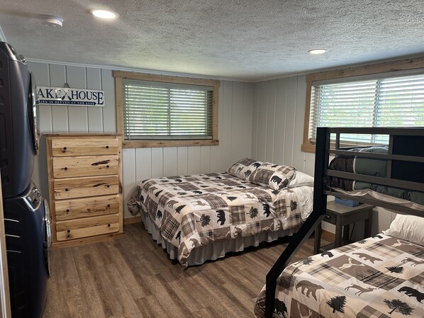 Une chambre compacte avec deux lits, une commode en bois et une pancarte sur laquelle on peut lire : « À ALEXHOUSE, la vie est plus belle au bord du lac ».