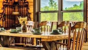 A wooden dining table set with plates, bowls, and a vase of flowers. - Mountain View l 3mi to Gatlinburg l Hot Tub l Game Room l Pack N Play (Gatlinburg)