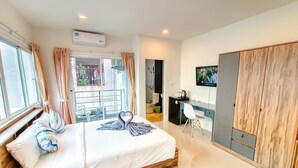 A modern hotel room with a large bed, a desk with a chair, a television, and a wardrobe. - Sailor Hotel Pattaya - Nice Rooms & Steps to Walking Street (Pattaya)