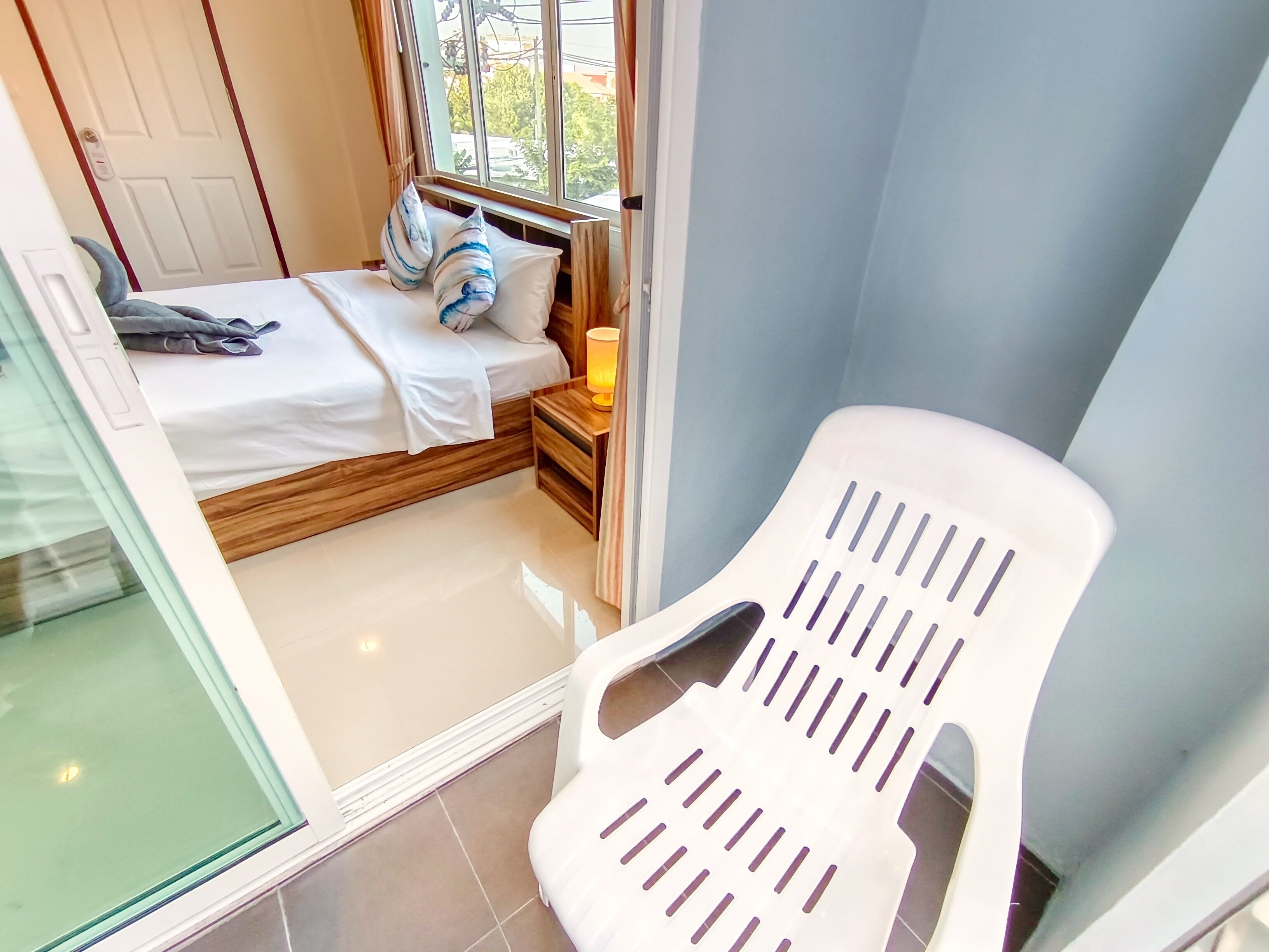 A bedroom with a bed, pillows, a nightstand, a lamp, and a window.