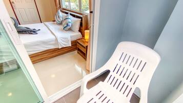 A bedroom with a bed, pillows, a nightstand, a lamp, and a window.
