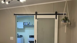 Une cuisine avec une porte coulissante donnant sur un espace buanderie, une plante suspendue et un luminaire au plafond.