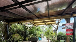 Un espace extérieur aménagé en terrasse, avec des sièges, un barbecue et une zone couverte où est affiché un panneau d’avertissement concernant la présence de caméras de surveillance et le caractère privé de la propriété.