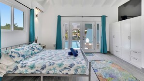 Ein Schlafzimmer mit Bett, Kleiderschrank, Fenster und Blick auf einen Außenpool.