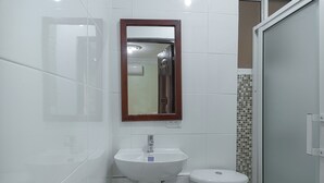 A bathroom with a white sink, a mirror, and a toilet.