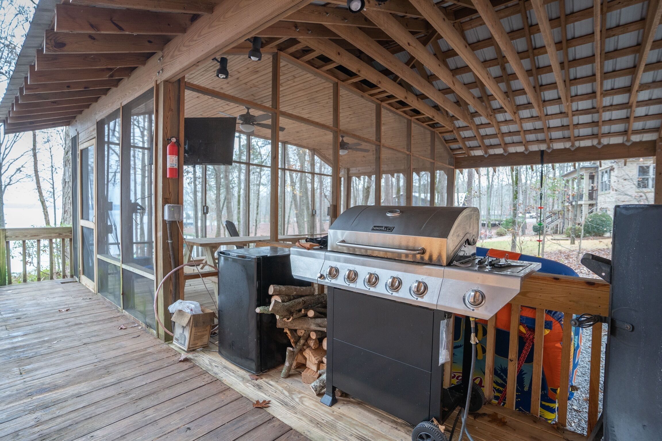 An outdoor covered patio with a grill and a fire pit.