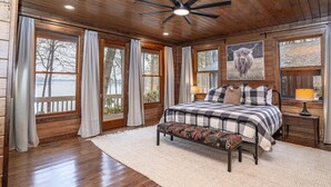 A bedroom with a large bed, wooden ceiling, and a view of a lake. - Lake Oconee Lake Front Cabin+Private Dock+Fire Pit+Fireplace+AMAZING VIEWS! (Eatonton)