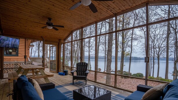 A wooden deck with a sofa, a chair, and a table, overlooking a lake. - Lake Oconee Lake Front Cabin+Private Dock+Fire Pit+Fireplace+AMAZING VIEWS! (Eatonton)