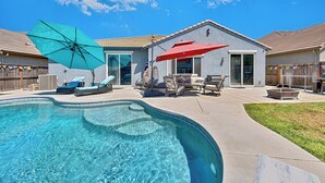 A backyard with a swimming pool, two umbrellas, and outdoor furniture. - Family Pool Home – Saltwater Pool & Fire Pit – 2 King Suites – Sleeps 12 (Elk Grove)