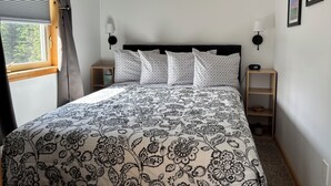 Een slaapkamer met een bed, twee nachtkastjes, een raam met gordijnen en wandlampen.