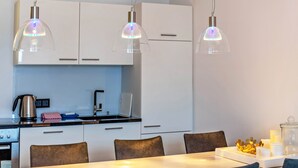 A modern kitchen with white cabinets, a dining table with chairs, and pendant lights. - Apartment "Haus Excelsior Top 30" with Mountain View, Balcony & Wi-Fi (Seefeld in Tirol)